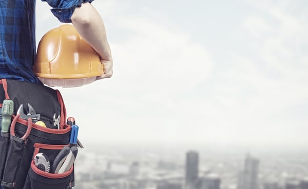 Close up of woman mechanic with yellow helmet in hand against city background