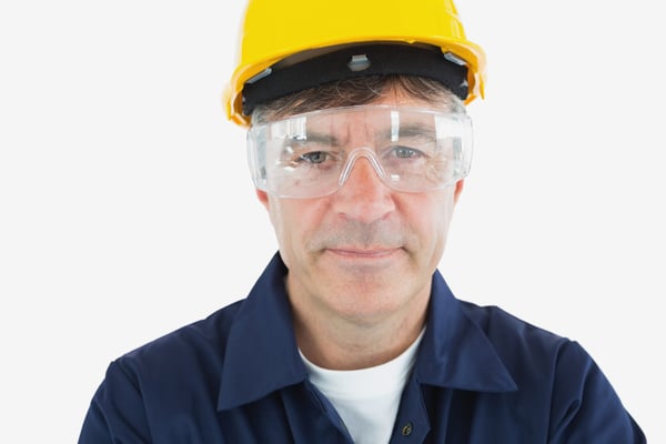 Close-up portrait of mature technician wearing protective glasses and hardhard over white background