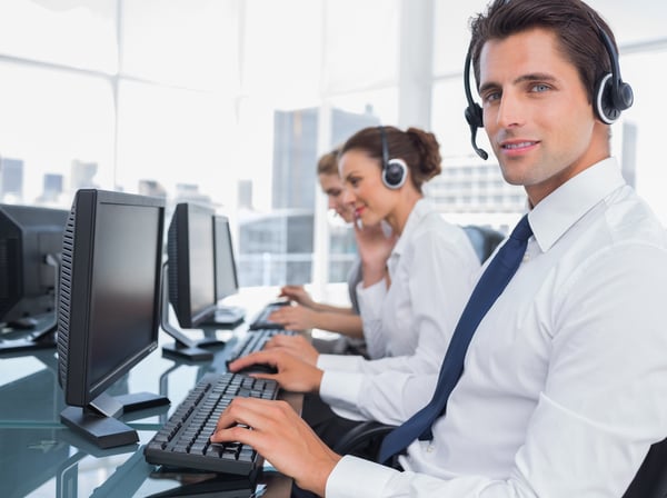 Portrait of smiling call center employee with colleagues behind