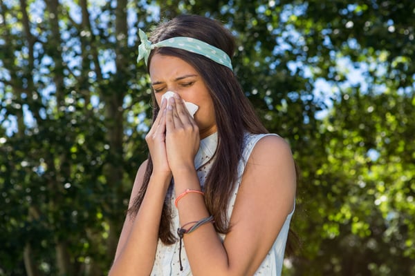 Pretty brunette blowing her nose on a summers day