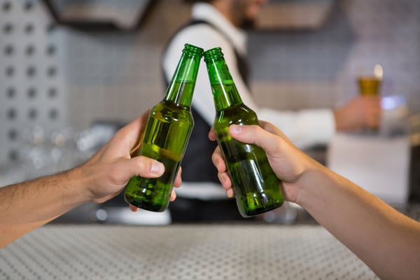 Two men toasting a bottle of beer in bar