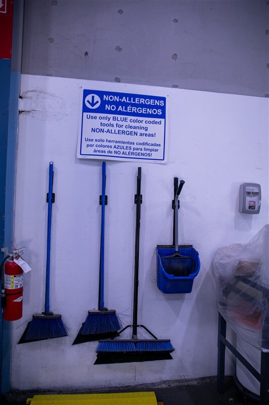 Quality assurance manager reviewing sanitation checklist on clipboard at stainless steel production workstation during shift