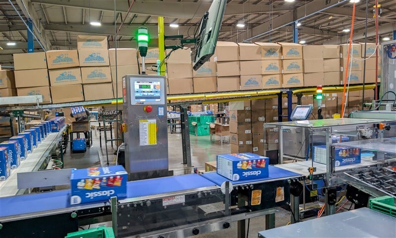 Checkweigher station on active conveyor line verifying multipack weight and count before palletizing