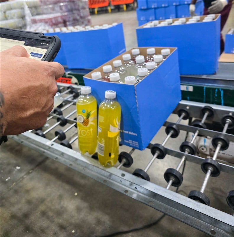Close-up of quality assurance inspector checking completed variety pack against specification sheet at inspection station
